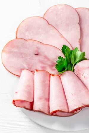Pieces of ham on a plate on a white background