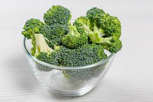 Pile broccoli in a glass bowl on a white background