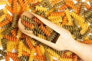 Pile of colorful macaroni with wooden spatula on the top