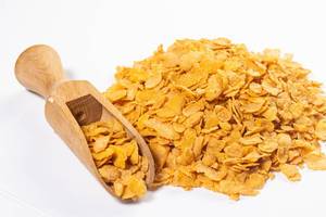 Pile of Corn Flakes with wooden measuring Spoon