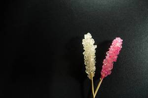 Pink and white rock candy on a black surface