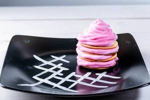 Pink dessert with cream on a black plate