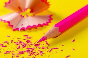 Pink pencil and shavings on yellow paper background
