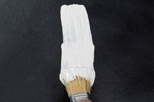 Pinsel auf schwarzem Hintergrund malt mit weißer Farbe