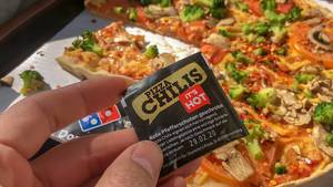 Pizza Chilis von Dominos mit roten Pfefferschoten, geschrotet und veganer Kap Verde Pizza im Hintergund