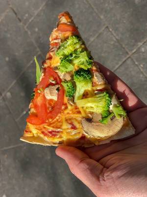 Pizzastück der neuen veganen Pizza Kap Verde von Dominos mit gesundem Belag wie Brokkoli, Tomaten, Pilze und veganem Reibeschmelz-Käse