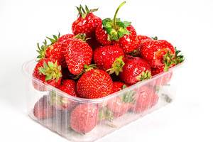 Plastic box with fresh strawberries on white