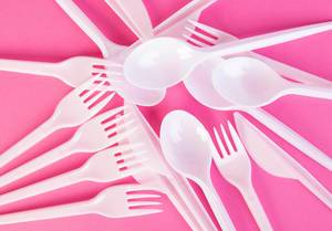 Plastic cutlery on pink background