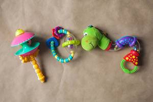 Plastic toys for newborn baby. Rattles on the paper background. Top view.