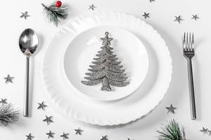 Plates with spoon and fork on a white table with Christmas silvery decor (Flip 2019)