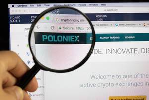 Poloniex logo on a computer screen with a magnifying glass