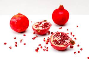 Pomegranate with red seeds on white surface