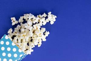 Popcorn in Papiertüte vor blauem Hintergrund
