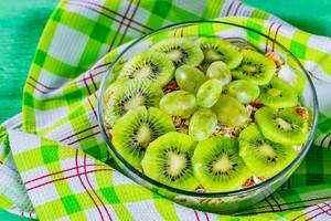Porridge with flakes with slices of fresh kiwi on a green background