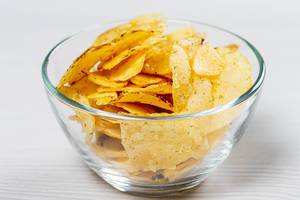 Potato chips in a glass bowl on a white table (Flip 2019)