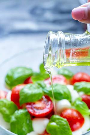 Pouring olive oil into fresh salad (Flip 2019) (Flip 2019)