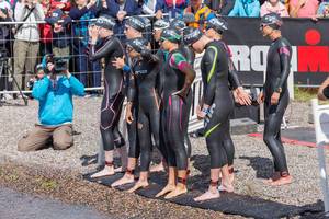 Professional female athletes with tracking footbands at the starting line of the Ironman competition, right before the first discipline swimming