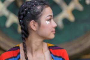 Profil einer Besucherin am Tomorrowland Festival mit glitzernden Applikationen in Haar und Gesicht