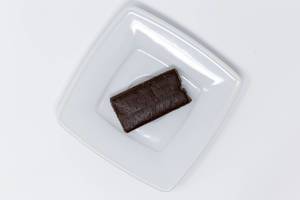 Pulsin Roher Schokoladen Brownie auf weißem Teller - Aufsicht