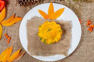 Pumpkin on a plate with autumn leaves, berries and cones. Autumn holidays background (Flip 2019)