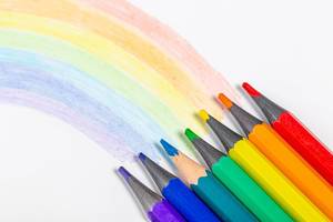 Rainbow and pencils of rainbow colors on white background
