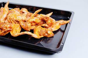 Raw chicken wings in pan, white background