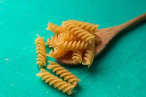 Raw pasta on wooden spoon