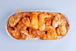 Raw spicy chicken wings in a pan, white background