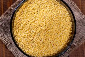 Raw yellow millet grits in a bowl on burlap