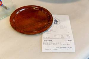 Rechnung aus einem spanischen Café in Barcelona, unter eine braune Untertasse geklemmt