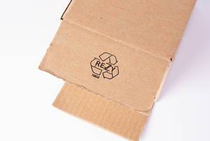 Recycling-Symbol auf Verpackung aus Pappkarton vor weißem Hintergrund