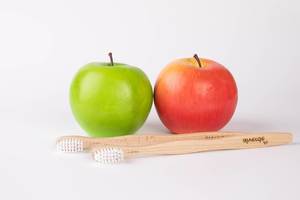 Red and green apple with wooden toothbrushes on white background (Flip 2019)