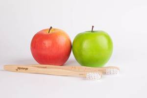 Red and green apple with wooden toothbrushes on white background