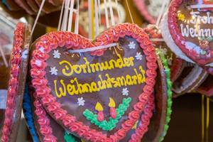 Red-brown gingerbread heart ornamented with candles and lettering "Dortmunder Weihnachtsmarkt" at a German christmas market