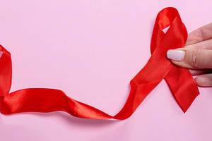 Red ribbon on pink background, symbol world aids day