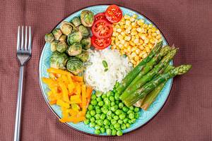 Rice with vegetables on a brown kitchen towel with a fork, top view (Flip 2020)