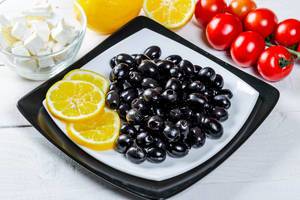 Ripe black olives with feta cheese, lemon and vegetables