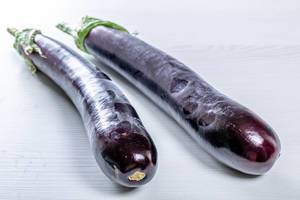 Ripe eggplant on white wooden background