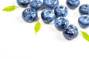 Ripe fresh blueberries with water drops on white wooden background