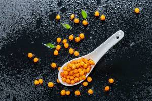 Ripe fruits of sea buckthorn with drops of water on a black background. View from above (Flip 2019)