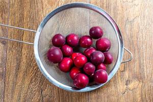 Ripe red plums in a sieve on a wooden table (Flip 2019)
