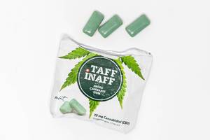 Ripped packaging of Taff Inaff Swiss Cannabis Gum contains CBD and shows three green gums on white table