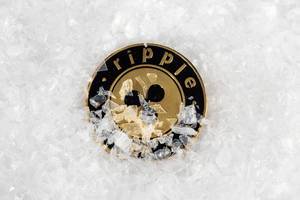 Ripple Münze liegt auf Eis, teilweise bedeckt mit Schneeflocken