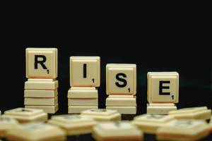 Rise word with scattered scrabble and black background