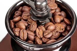 Roasted coffee beans in a mechanical coffee grinder, close-up