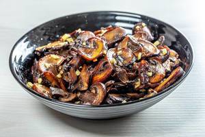 Roasted mushrooms with garlic on black bowl (Flip 2019)