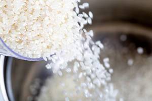 Roher Reis wird in einen Kochtopf gegossen