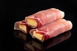 Rolled Pork Ham with yellow Cheddar cheese above black background