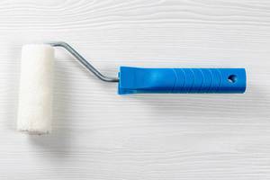 Roller paint brush on white wooden background