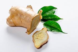 Root ginger on white background with green leaves (Flip 2019)